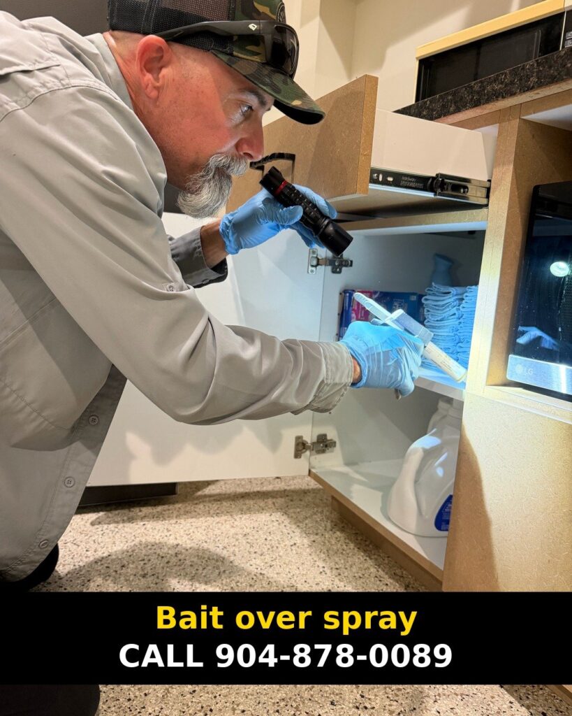 Technician with a flashlight and bait syringe at an open cabinet, with a "Bait over spray" caption bar